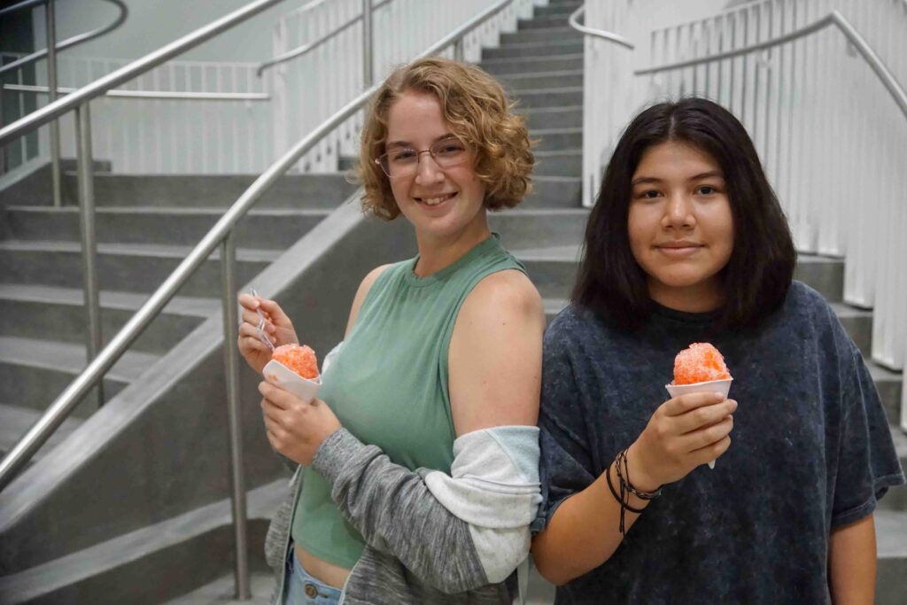 Two people stand before a staircase with icecream cones.