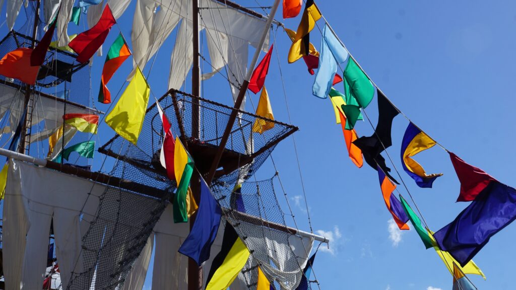 Colorful flags hang along ropes strewn across an old sailboat.